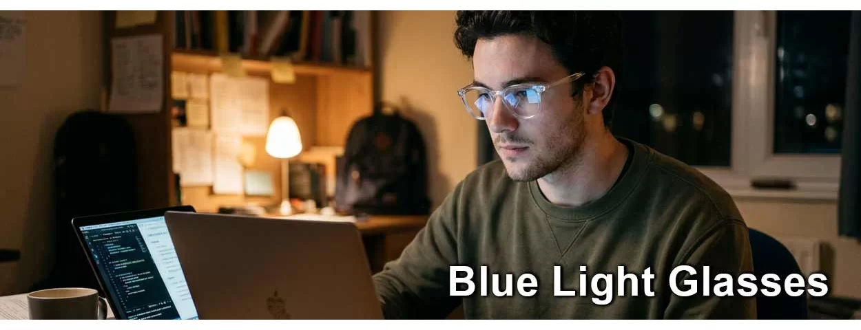 Young man wearing blue block glasses looking at his laptop while studying in NZ