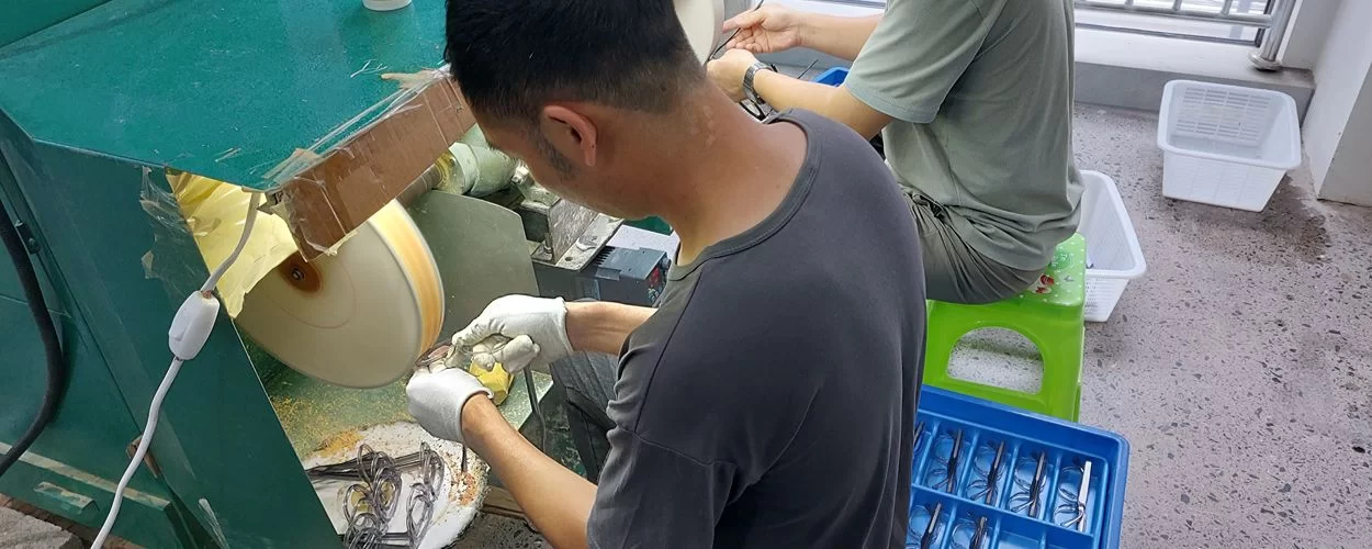 Eyewear factory worker polishing sunglasses frames before final assembly